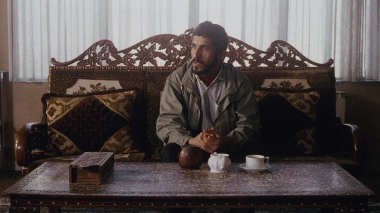 Hossain Sabzan as himself sitting on couch with hands cupped together in Close-Up