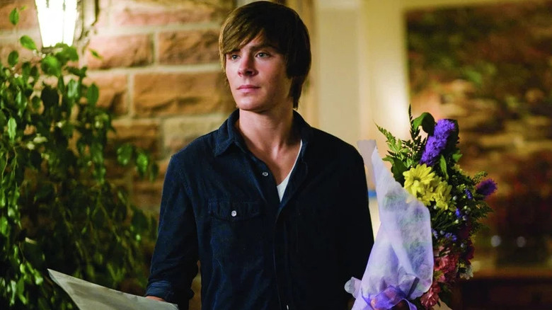 Zac Efron as Mike in blue shirt holding flowers in 17 Again
