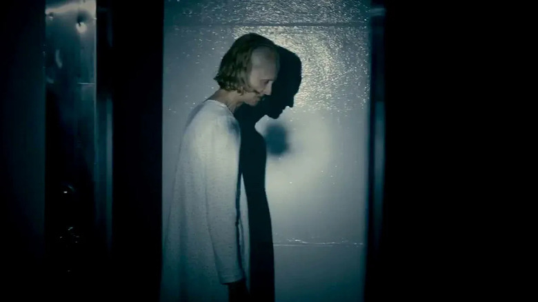 Jill Larson as Deborah Logan in The Taking of Deborah Logan, looking somber and spooky as she stares at the ground, her silhouette cast behind her.