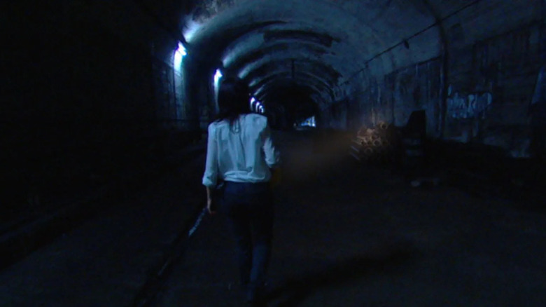 Bel Deliá as Natasha Warner in The Tunnel, seen from behind walking down a dark and spooky... tunnel.