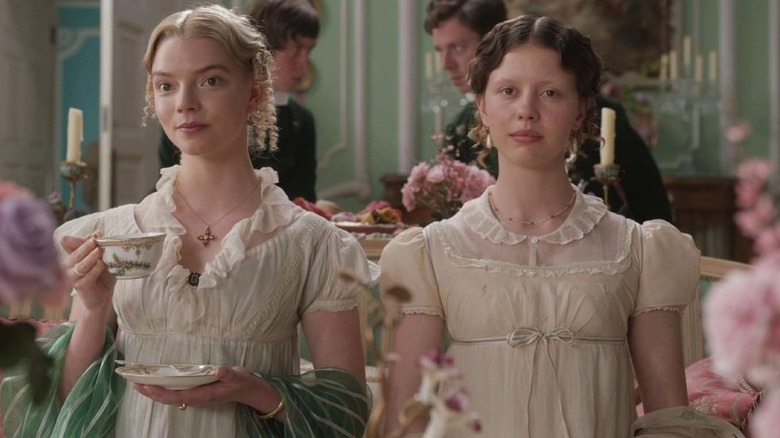 Anya Taylor-Joy as Emma Woodhouse sits next to Mia Goth as Harriet Smith in Emma.