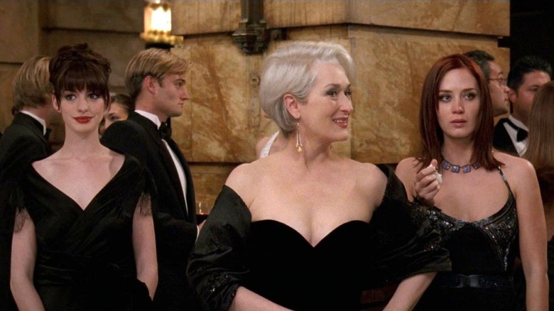 Anne Hathaway as Andy Sachs stands next to Meryl Streep as Miranda Priestly, and Emily Blunt as Emily Charlton in The Devil Wears Prada