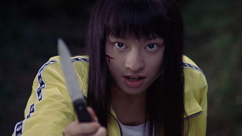 A wounded Takako Chigusa (Chiaki Kuriyama) holds up a knife menacingly in Battle Royale