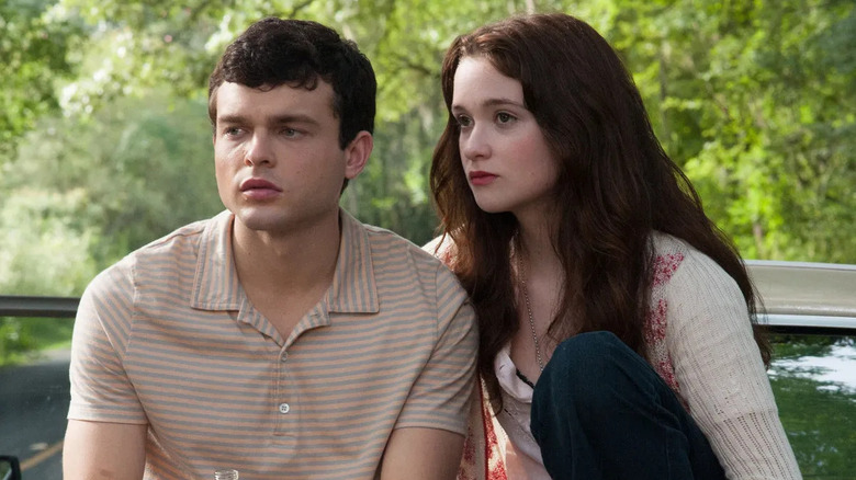 Ethan Wate (Alden Ehrenreich) and Lena Duchannes (Alice Englert) sit next to each other by their car in Beautiful Creatures