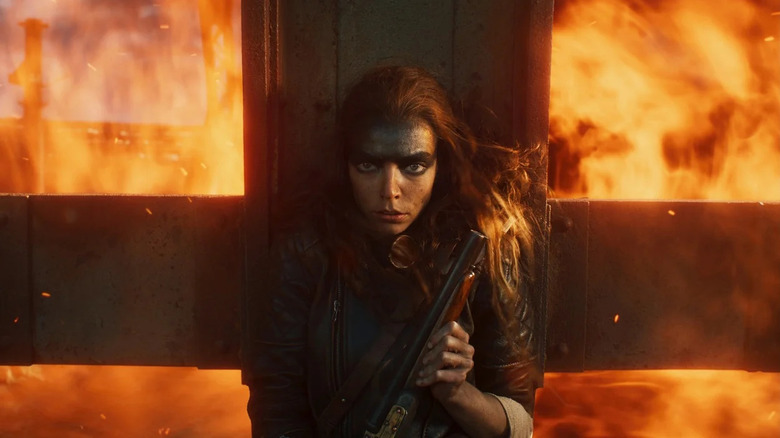 Furiosa (Anya Taylor-Joy) stoically takes cover from a fiery explosion in Furiosa: A Mad Max Saga