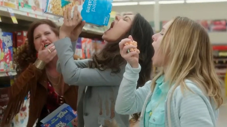 Carla (Kathryn Hahn), Amy (Mila Kunis), and Kiki (Kristen Bell) eating cereal at a supermarket in Bad Moms