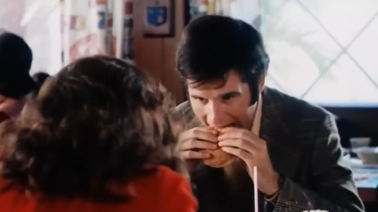 Lenny (Charles Grodin) biting into a burger in The Heartbreak Kid