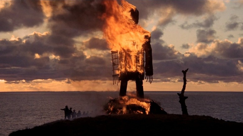A wicker man statue burns as villagers dance in The Wicker Man
