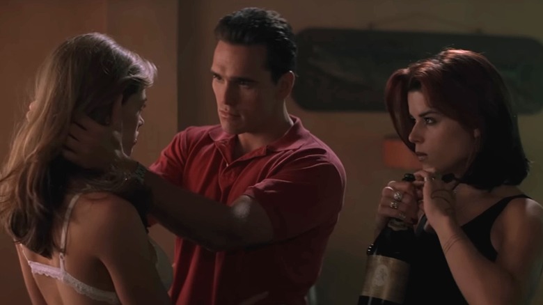 Matt Dillon as Sam with hands around Denise Richards as Kelly and Neve Campbell as Suzie holding bottle of champagne in Wild Things