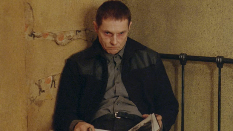 Sean Harris as Phillip Cornell, scowling and holding a book in Possum