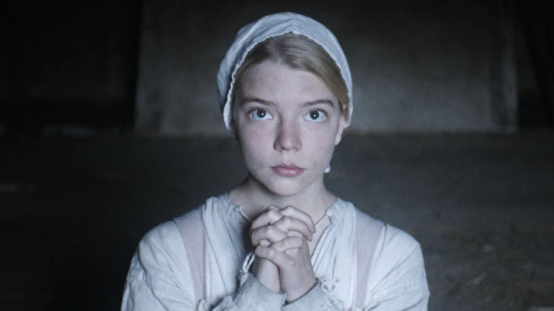 Anya Taylor-Joy as Thomasin, clasping hands in prayer in The Witch