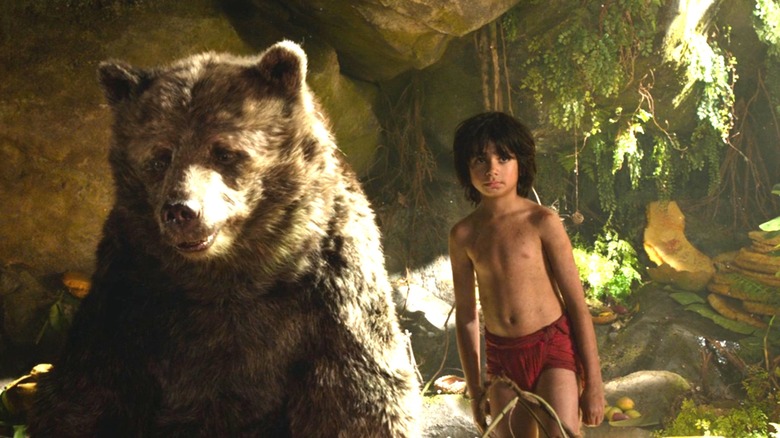 Mowgli (Neel Sethi) standing next to Baloo the bear in The Jungle Book