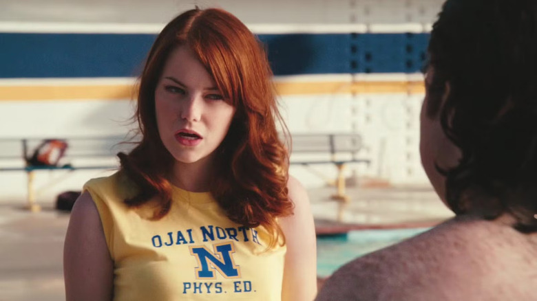 Emma Stone in her gym class t-shirt talking to a boy next to the pool Easy A