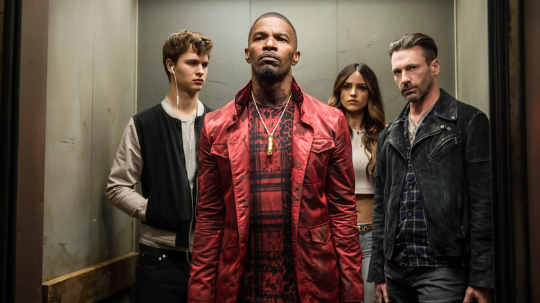 The crew from Baby Driver standing in an elevator as the door opens