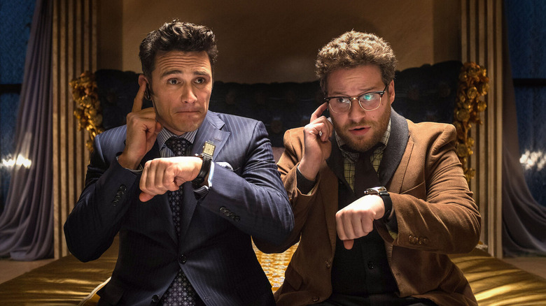 James Franco and Seth Rogen as David Skylark and Aaron Rappaport, sitting on a bed and checking watches together in The Interview