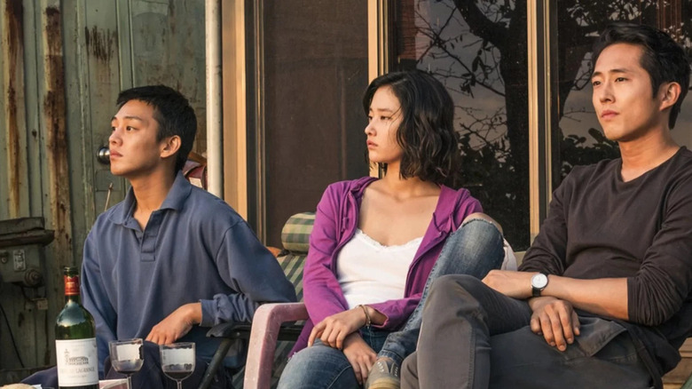 Lee Jong-su (Yoo Ah-in), Shin Hae-mi (Jeon Jong-seo), and Ben (Steven Yeun) watch the sunset on a porch in Burning (2018)