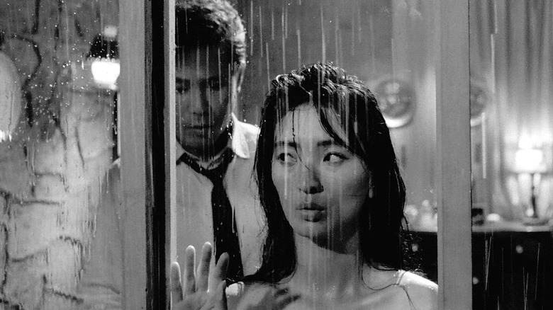 Kim Dong-sik (Kim Jin-kyu) approaches Myung-sook (Lee Eun-shim) behidn a rainy window in The Housemaid (1960)