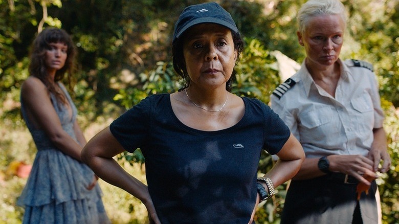 Abigail (Dolly de Leon) stands in front of Yaya (Charlbi Dean) and Paula (Vicki Berlin) in the jungle in Triangle of Sadness