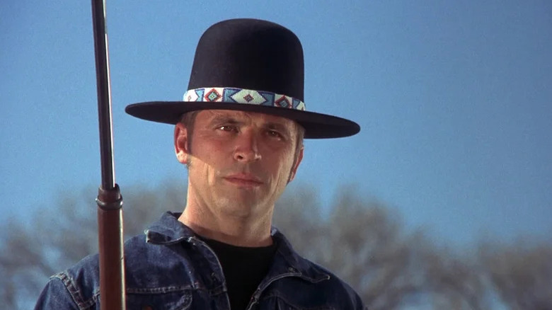 Billy Jack (Tom Laughlin) stands holding a rifle in Billy Jack