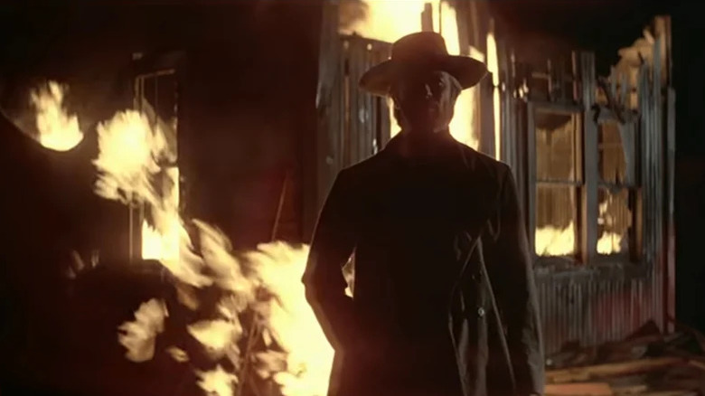 The stranger (Clint Eastwood) stands in front of a burning building in High Plains Drifter