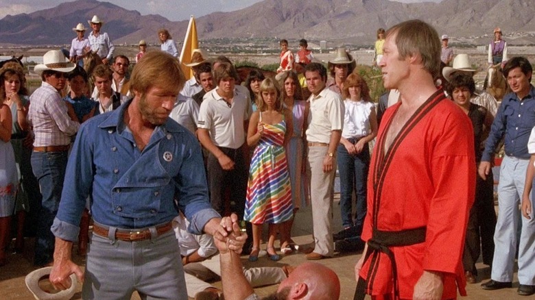 Jim McQuade (Chuck Norris) holds a man by his hand in Lone Wolf McQuade