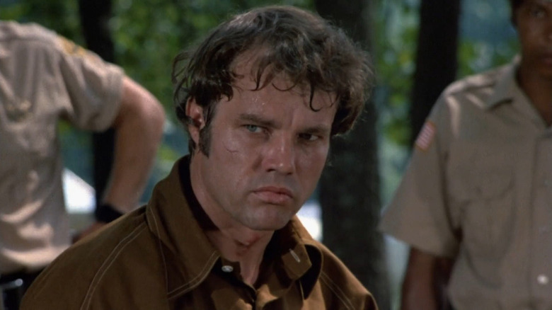 Buford Pusser (Joe Don Baker) stands disheveled and sweaty with deputies behind him in Walking Tall (1973)