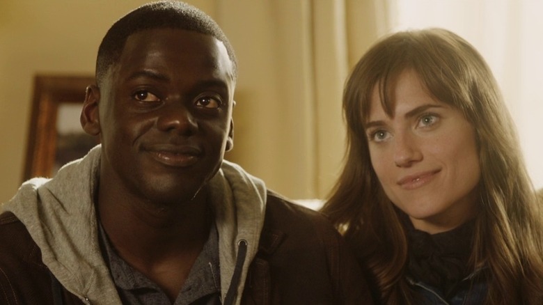 Daniel Kaluuya as Chris in hoody smiling sitting next to Allison Williams as Rose in Get Out