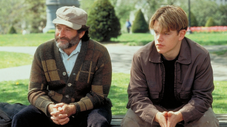Robin William as Sean sitting next to Matt Damon as Will on a park bench in Good Will Hunting
