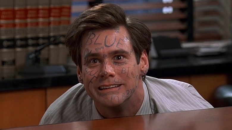 Jim Carrey as Fletcher hiding behind his desk with "BLUE" written all over his face in Liar Liar