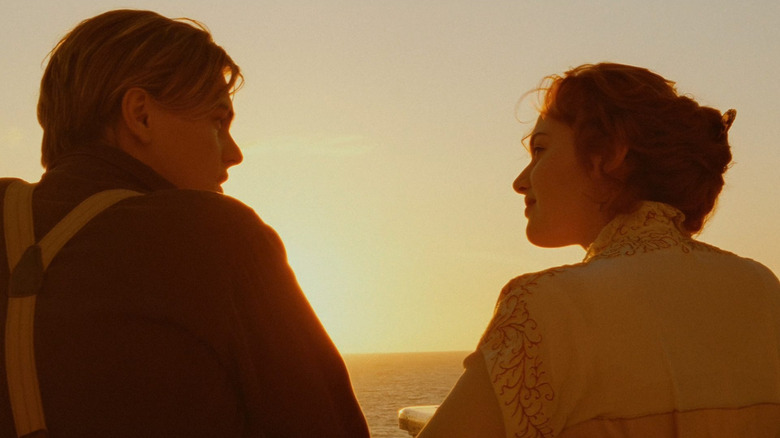 Leonardo DiCaprio as Jack standing next to Kate Winslet as Rose looking out at the sunset over the ocean in Titanic