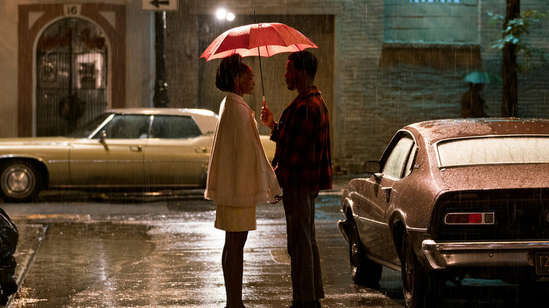 KiKi Layne and Stephan James as Tish and Fonny standing under an umbrella on a Harlem street in If Beale Street Could Talk