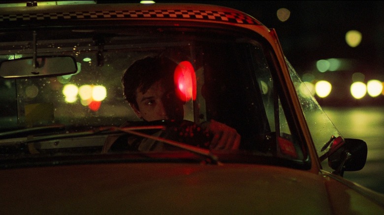 Robert De Niro as Travis Bickle behind the wheel of a taxi at night in Taxi Driver