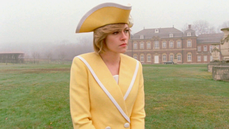 Kristen Stewart as Diana, Princess of Wales, dressed in yellow and standing on the grounds in fog in Spencer.