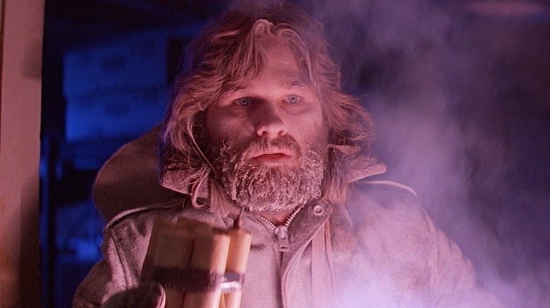 Kurt Russell as R.J. MacReady holding a flare in The Thing
