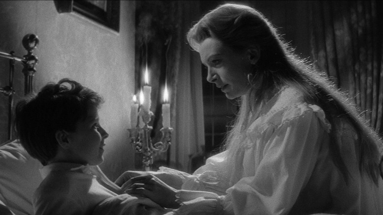 Deborah Kerr as Miss Giddens and Martin Stephens as Miles in The Innocents, as Miss Giddens tucks Miles into bed.