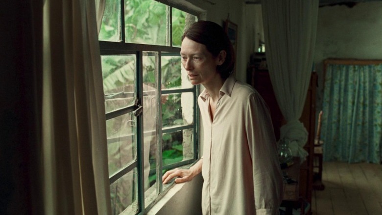 Tilda Swinton as Jessica looking out a glass pane window in Memoria