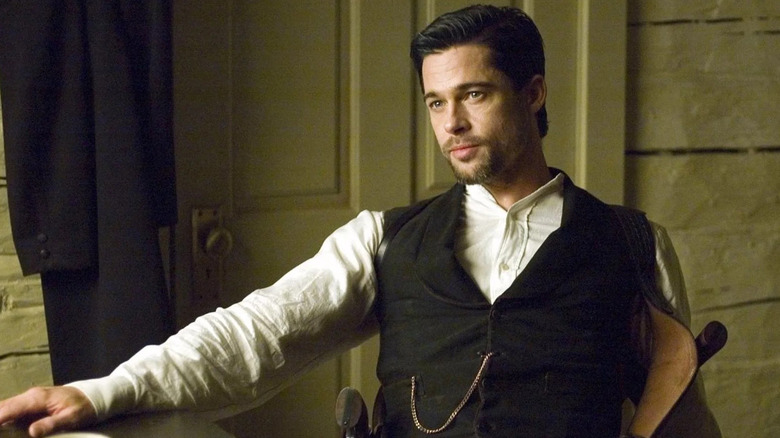 Brad Pitt as Jesse James in The Assassination of Jesse James by the Coward Robert Ford, in his white button-up and vest as he sits in a house, looking off past the frame.