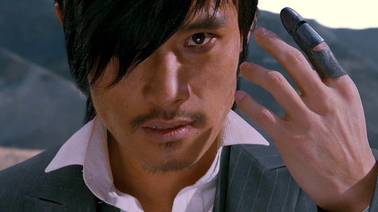 A close-up of Jung Woo-sung as Park Do-won, "the Good" in The Good, The Bad The Weird, looking intensely on as he raises his hand to his face.