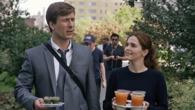 Glen Powell as Charlie Young and Zoey Deutch as Harper Moore carrying drinks in Set It Up