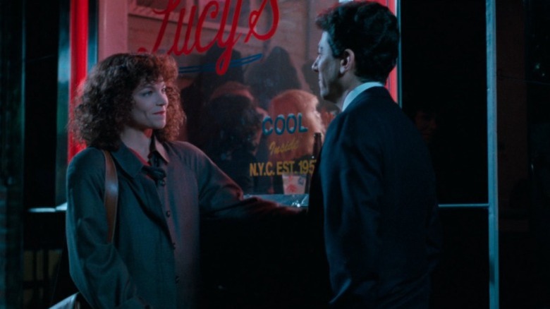 Amy Irving as Isabelle Grossman and Peter Riegert as Sam Posner standing before each other next to a store window and smiling in Crossing Delancey