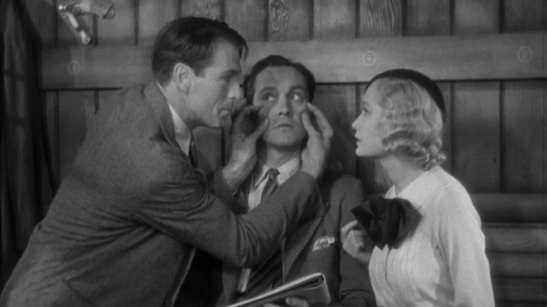 Gary Cooper as George Curtis pinching the cheeks of Fredric March as Tom Chambers while Miriam Hopkins as Gilda Farrell looks on in Design for Living