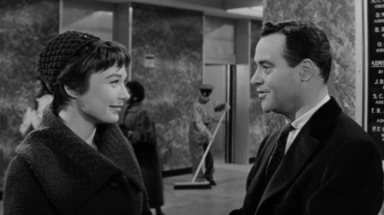 Shirley MacLaine as Fran Kubelik and Jack Lemmon as C.C. "Buddy" Baxter smiling at each other next to an elevator hall in The Apartment