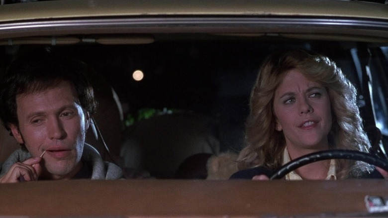Meg Ryan as Sally Albright driving a car while Billy Crystal as Harry Burns picks his tooth in the passenger's seat in When Harry Met Sally...