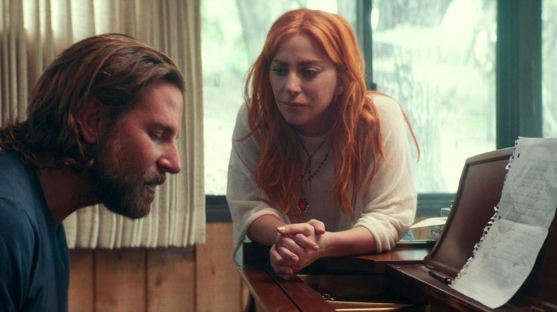 Bradley Cooper as Jack plays the piano while Lady Gaga as Ally watches in A Star is Born
