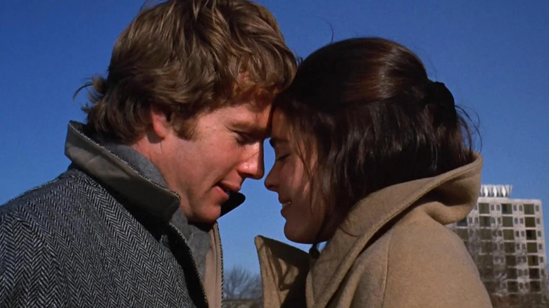 Ryan O'Neal as Oliver Barrett IV touches heads with Ali MacGraw as Jenny Cavilleri outside in Love Story
