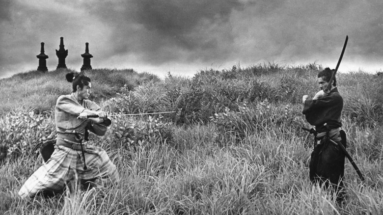 Tsugumo Hanshirō (Tatsuya Nakadai) and Omodaka Hikokuro (Tetsurō Tanba) face each other on a grassy hill with swords drawn in Harakiri (1960)