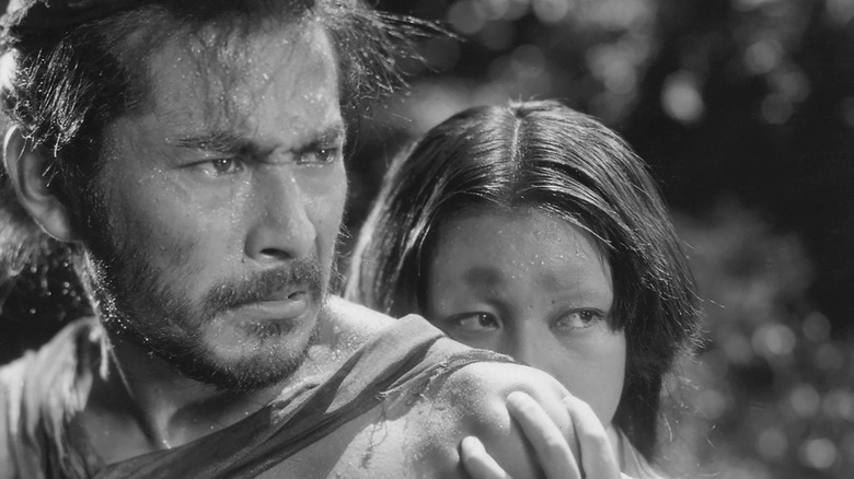 Masago (Machiko Kyō) hides behind Tajōmaru (Toshiro Mifune) in Rashomon