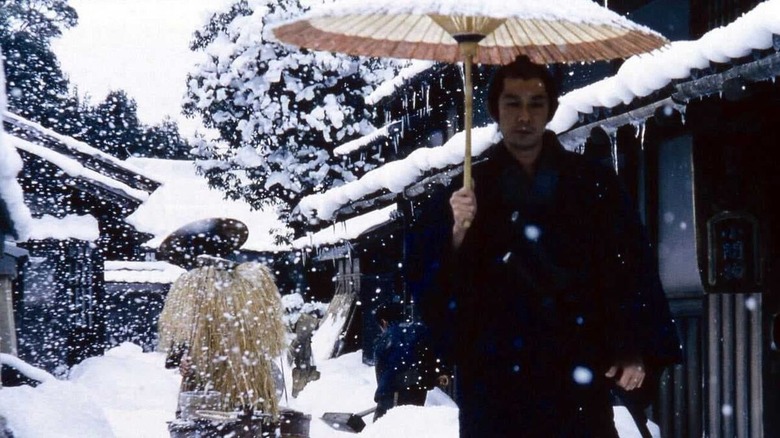Munezo Katagiri (Masatoshi Nagase) walks through snow with a parasol in The Hidden Blade