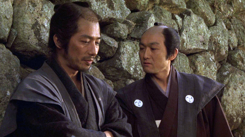 Seibei Iguchi (Hiroyuki Sanada) speaks with Iinuma Michinojo (Mitsuru Fukikoshi) by a stone wall in The Twilight Samurai