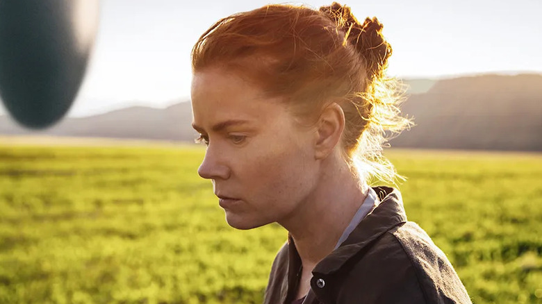 Amy Adams as Louise Banks, walking past a spaceship in a field in Arrival.